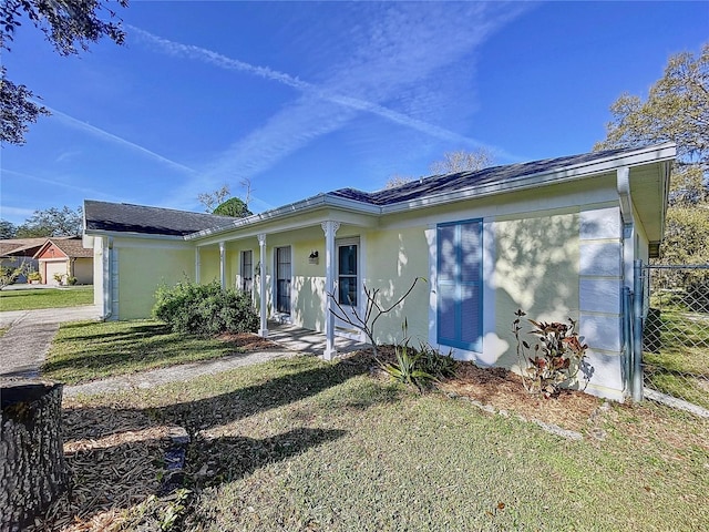 ranch-style house with stucco siding, covered porch, and a front yard