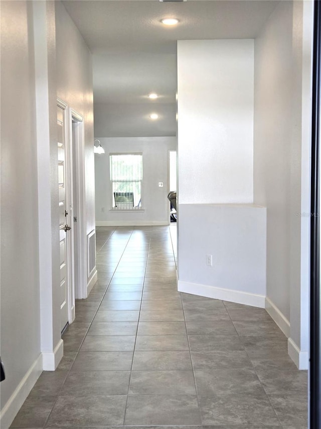 hallway featuring tile patterned floors and baseboards