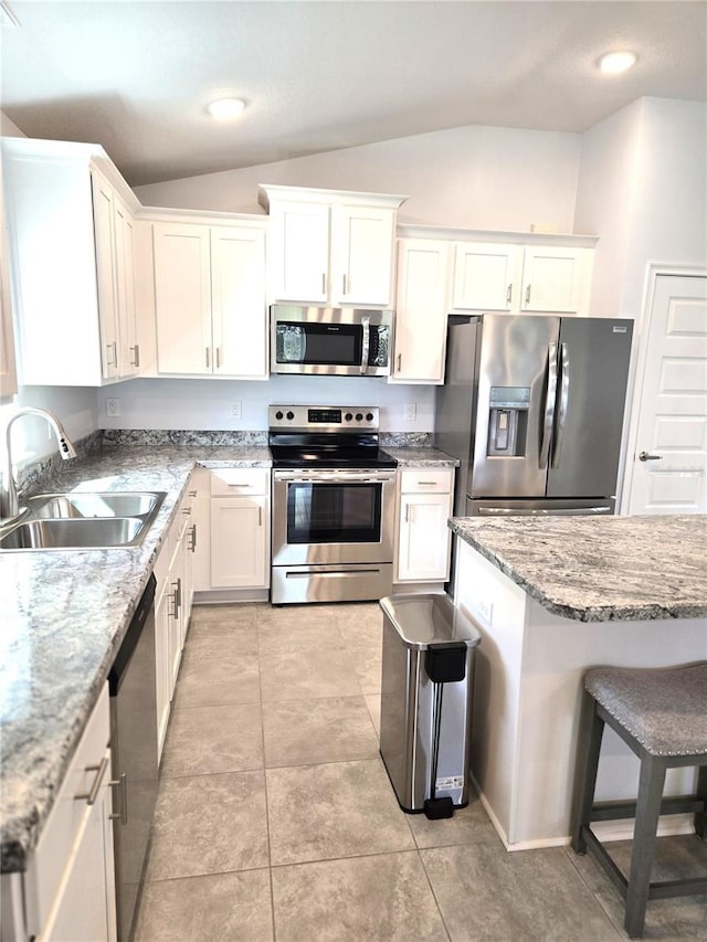 kitchen featuring lofted ceiling, white cabinetry, appliances with stainless steel finishes, and a sink