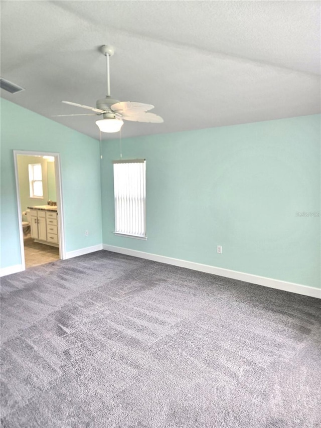 empty room featuring lofted ceiling, carpet floors, visible vents, and baseboards