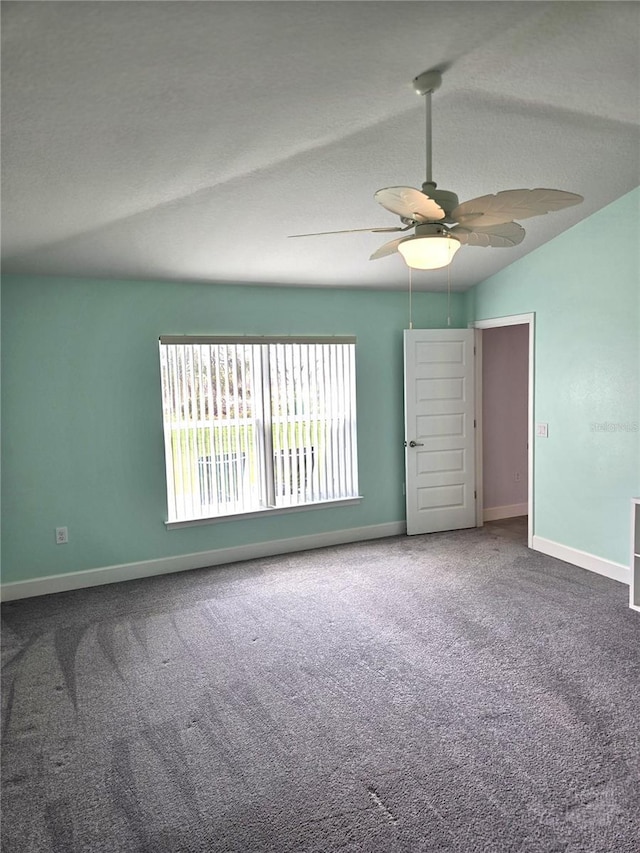 empty room featuring vaulted ceiling, carpet floors, ceiling fan, and baseboards