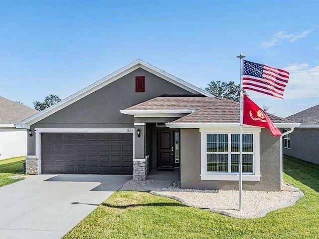 view of front of home with roof with shingles, stucco siding, concrete driveway, an attached garage, and a front yard