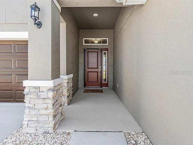 entrance to property featuring a garage and stucco siding