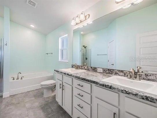 full bathroom featuring a garden tub, a sink, visible vents, and a shower stall