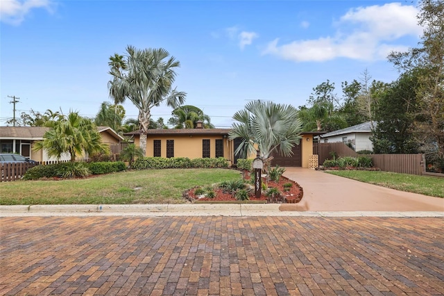 view of front of house featuring a garage, concrete driveway, fence, a front yard, and stucco siding