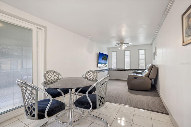 dining space with light colored carpet, ceiling fan, baseboards, and light tile patterned floors