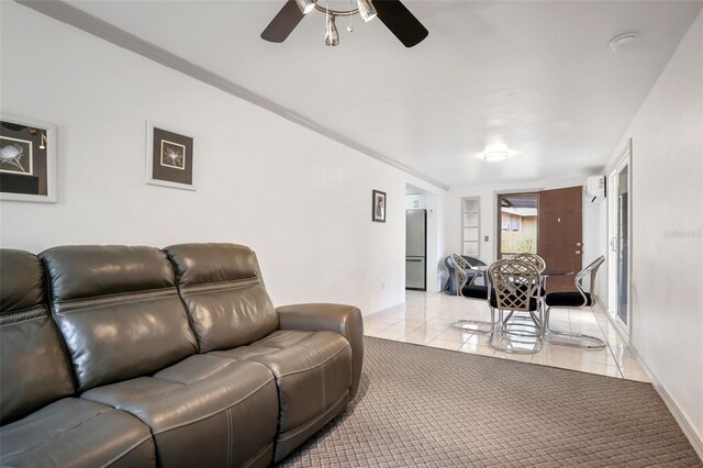 living area featuring light tile patterned floors, baseboards, a ceiling fan, and light colored carpet