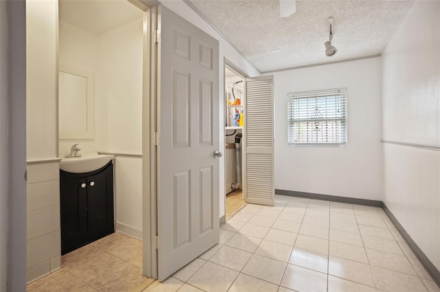 bathroom featuring baseboards, tile patterned flooring, a textured ceiling, vanity, and track lighting