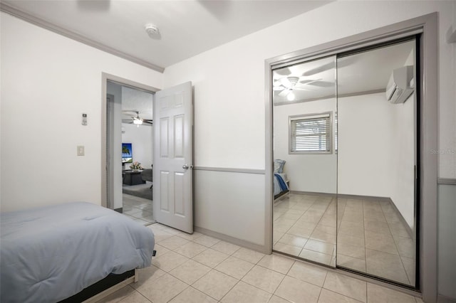 bedroom with crown molding, light tile patterned floors, a closet, a wall mounted AC, and baseboards