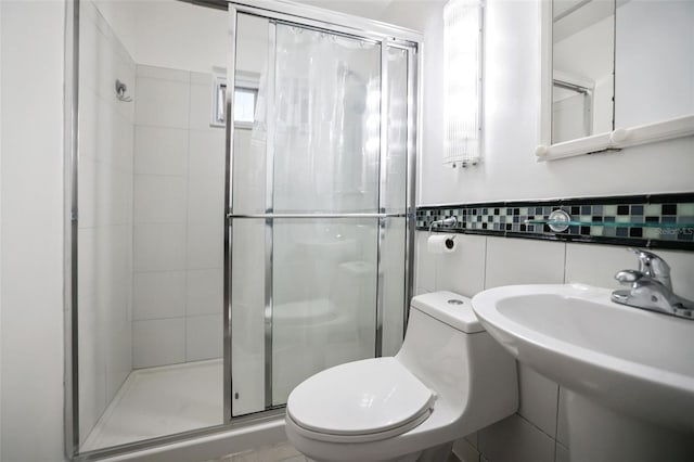 bathroom featuring a wainscoted wall, tile walls, toilet, a sink, and a shower stall