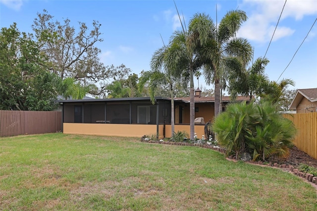 rear view of house featuring a sunroom, a fenced backyard, and a yard