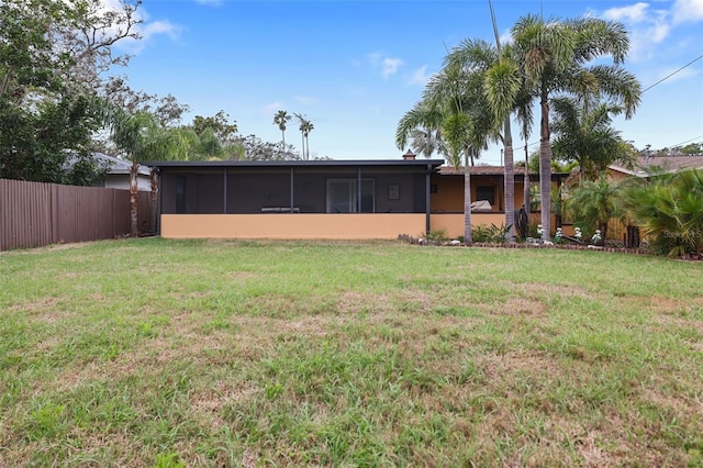 back of house with a lawn, a fenced backyard, and a sunroom