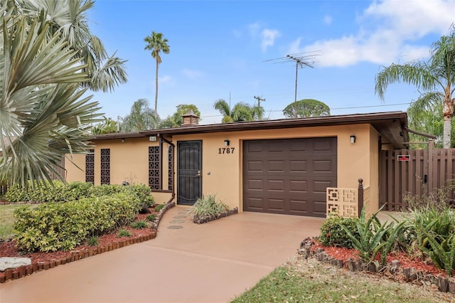 ranch-style home featuring an attached garage, fence, concrete driveway, and stucco siding