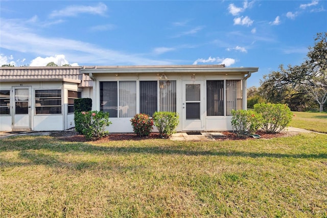 rear view of property featuring a lawn and a sunroom