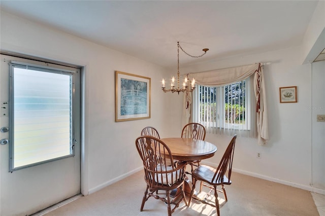 carpeted dining area with a notable chandelier and baseboards