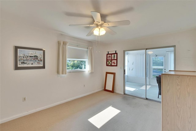 unfurnished room with a ceiling fan, light colored carpet, and baseboards