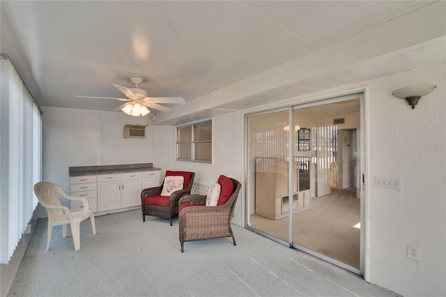 living area featuring light carpet, visible vents, a wall unit AC, and a ceiling fan