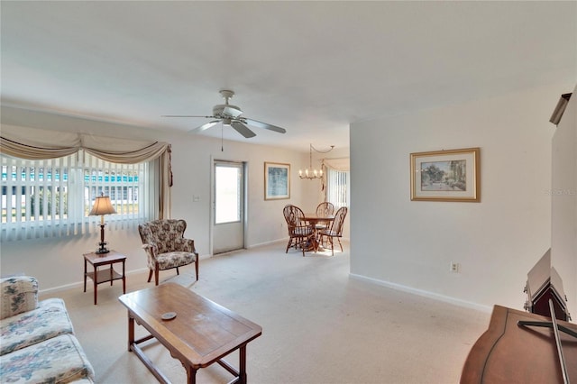 living room with light carpet, baseboards, and ceiling fan with notable chandelier