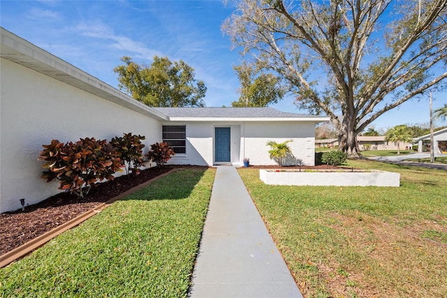 entrance to property featuring a lawn and stucco siding