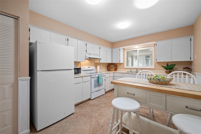 kitchen with light countertops, light tile patterned flooring, white cabinetry, white appliances, and under cabinet range hood