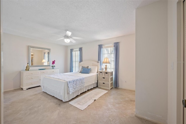 bedroom with a ceiling fan, light tile patterned flooring, and a textured ceiling