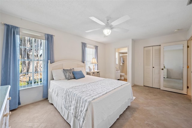 bedroom featuring a closet, connected bathroom, a textured ceiling, ceiling fan, and baseboards