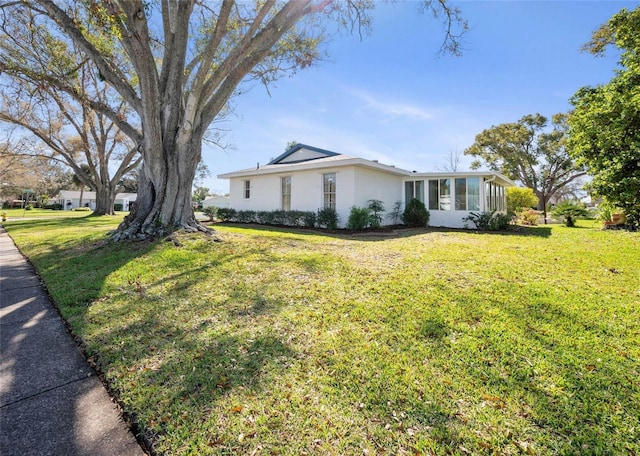 view of home's exterior with a sunroom, a lawn, and stucco siding