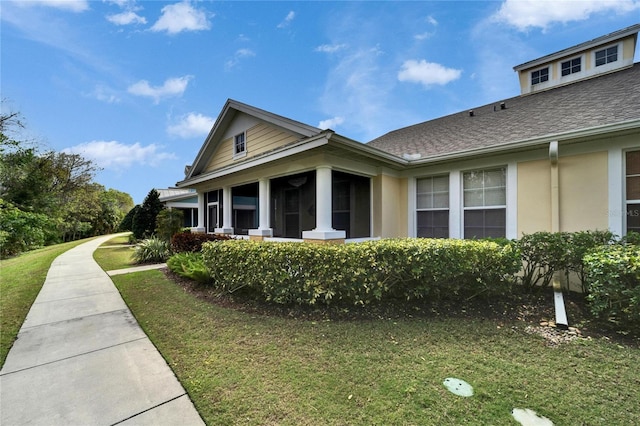 view of home's exterior with a shingled roof, a lawn, and stucco siding