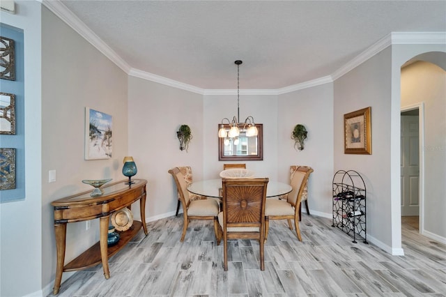 dining area featuring light wood-type flooring, arched walkways, baseboards, and an inviting chandelier