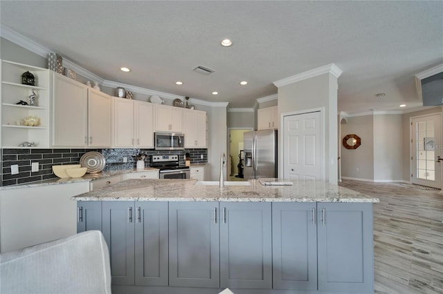 kitchen with light stone counters, a center island, stainless steel appliances, white cabinetry, and open shelves