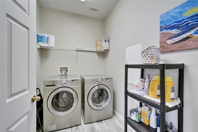 laundry room with laundry area, visible vents, baseboards, light wood finished floors, and washer and clothes dryer