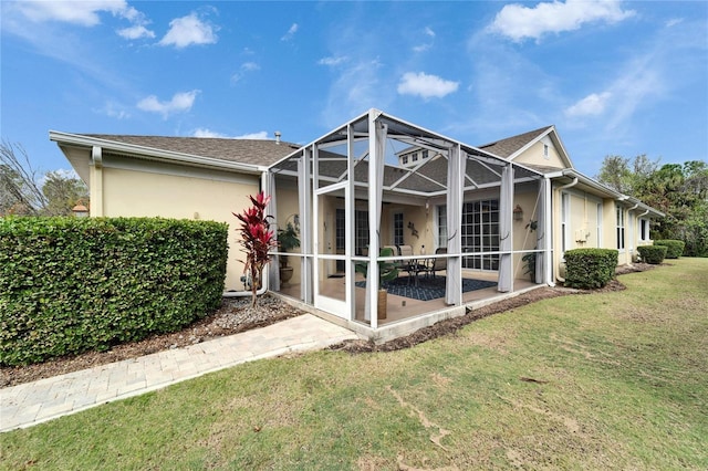 rear view of property with a lanai, a patio, a lawn, and stucco siding