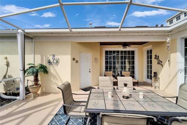 view of patio with ceiling fan, outdoor dining space, and a lanai