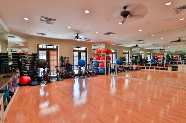 workout area with light wood finished floors, visible vents, and crown molding