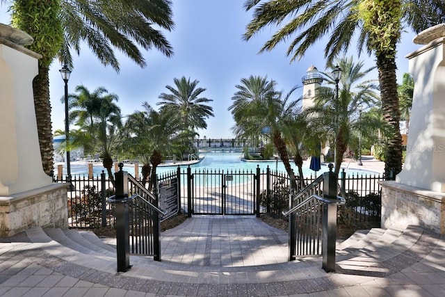 view of gate with a water view, fence, and a community pool