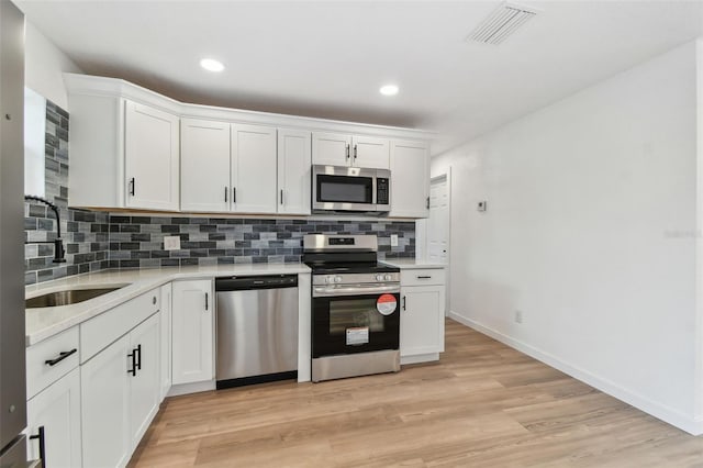 kitchen with light countertops, appliances with stainless steel finishes, a sink, and visible vents