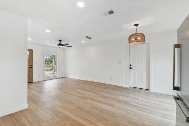 empty room with baseboards, a textured ceiling, visible vents, and light wood-style floors