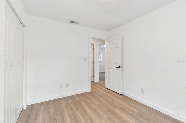 unfurnished bedroom featuring a closet, baseboards, visible vents, and light wood finished floors