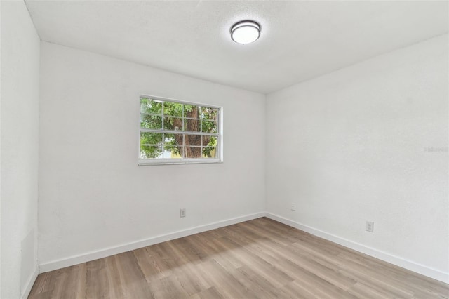 spare room with a textured ceiling, baseboards, and wood finished floors