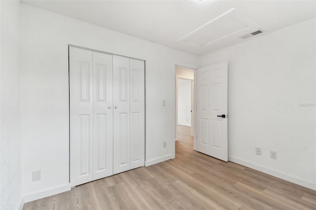 unfurnished bedroom featuring light wood finished floors, attic access, visible vents, and baseboards