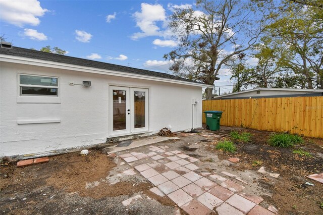 rear view of house with roof with shingles, fence, french doors, a patio area, and stucco siding