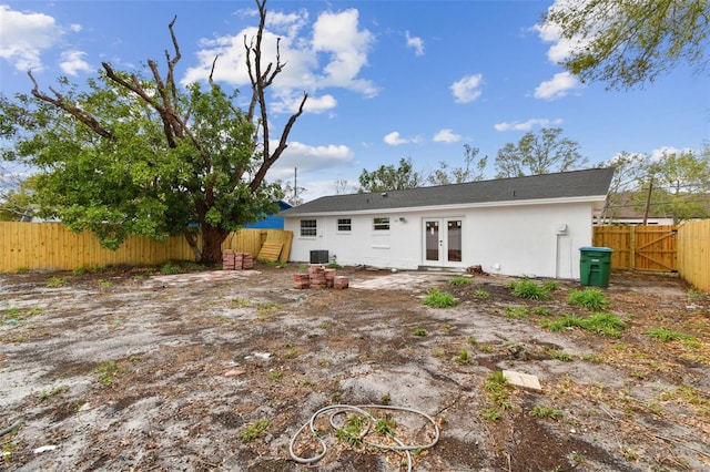 back of house featuring central AC unit, stucco siding, fence, and french doors