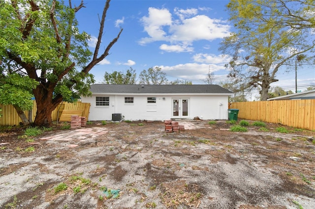 back of house featuring french doors, stucco siding, fence, and central air condition unit