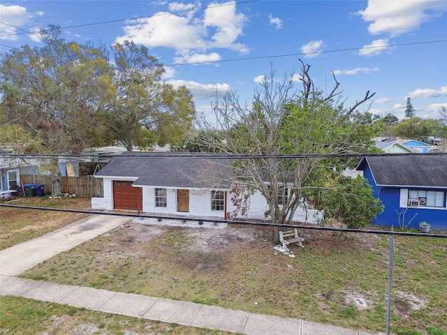 ranch-style home featuring concrete driveway and fence