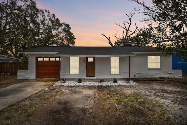 ranch-style home featuring concrete driveway, an attached garage, covered porch, fence, and stucco siding