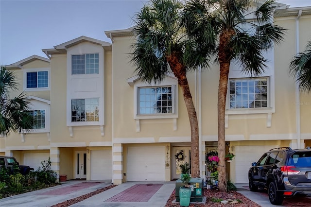 townhome / multi-family property with a garage, driveway, and stucco siding