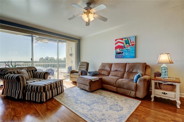 living area with wood finished floors, ceiling fan, and ornamental molding