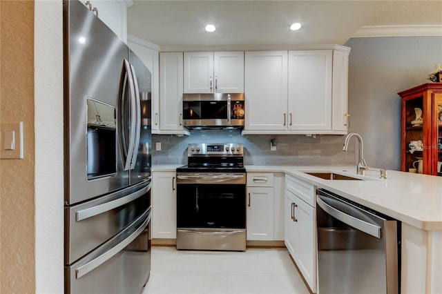 kitchen with a sink, backsplash, stainless steel appliances, a peninsula, and light countertops