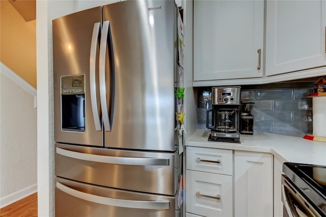 kitchen with light countertops, white cabinets, backsplash, and appliances with stainless steel finishes