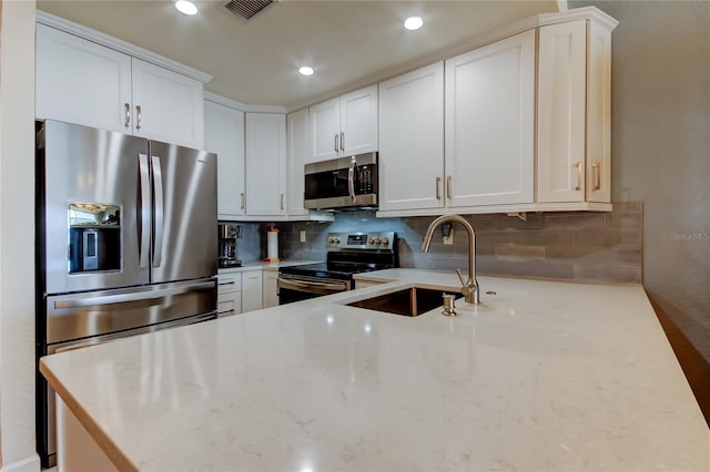 kitchen with decorative backsplash, visible vents, appliances with stainless steel finishes, and a sink